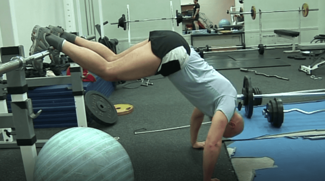 Mark Pollock performing press-ups in a blue tshirt and shorts while his legs are raised over a bar.
