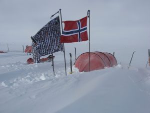 Marks South Pole Flag, which features all the faces of his supporters around the word, is pitched in the snow beside the Norwegian flag in front of a red tent.